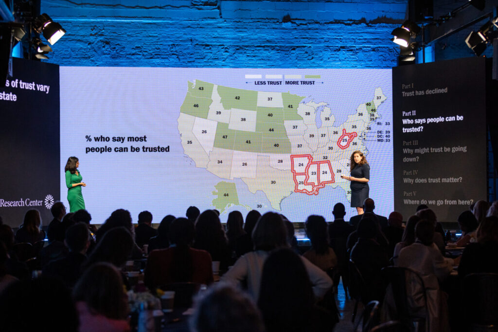 Two speakers on stage in front of a projected U.S. map.
