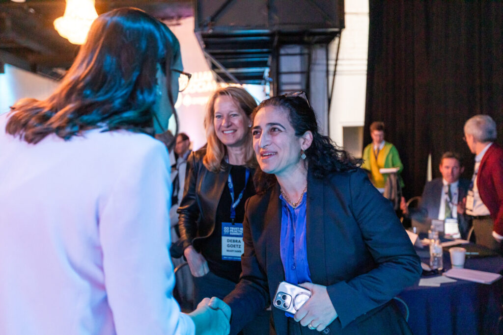 Two attendees shaking hands and smiling at a conference.