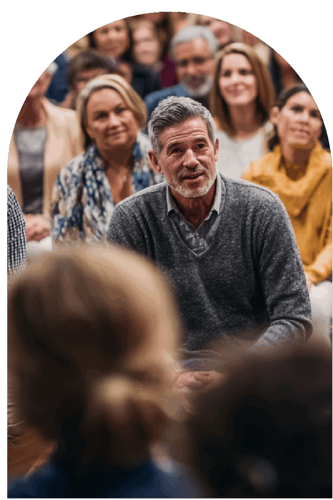 Man speaking in an audience discussion with others seated behind him