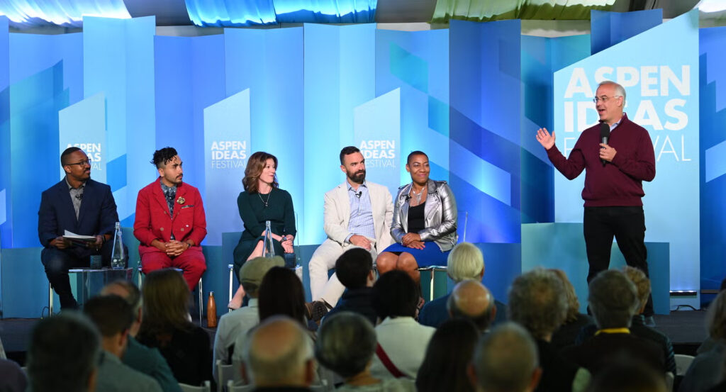 Panelists seated on stage at the Aspen Ideas Festival, audience in foreground.