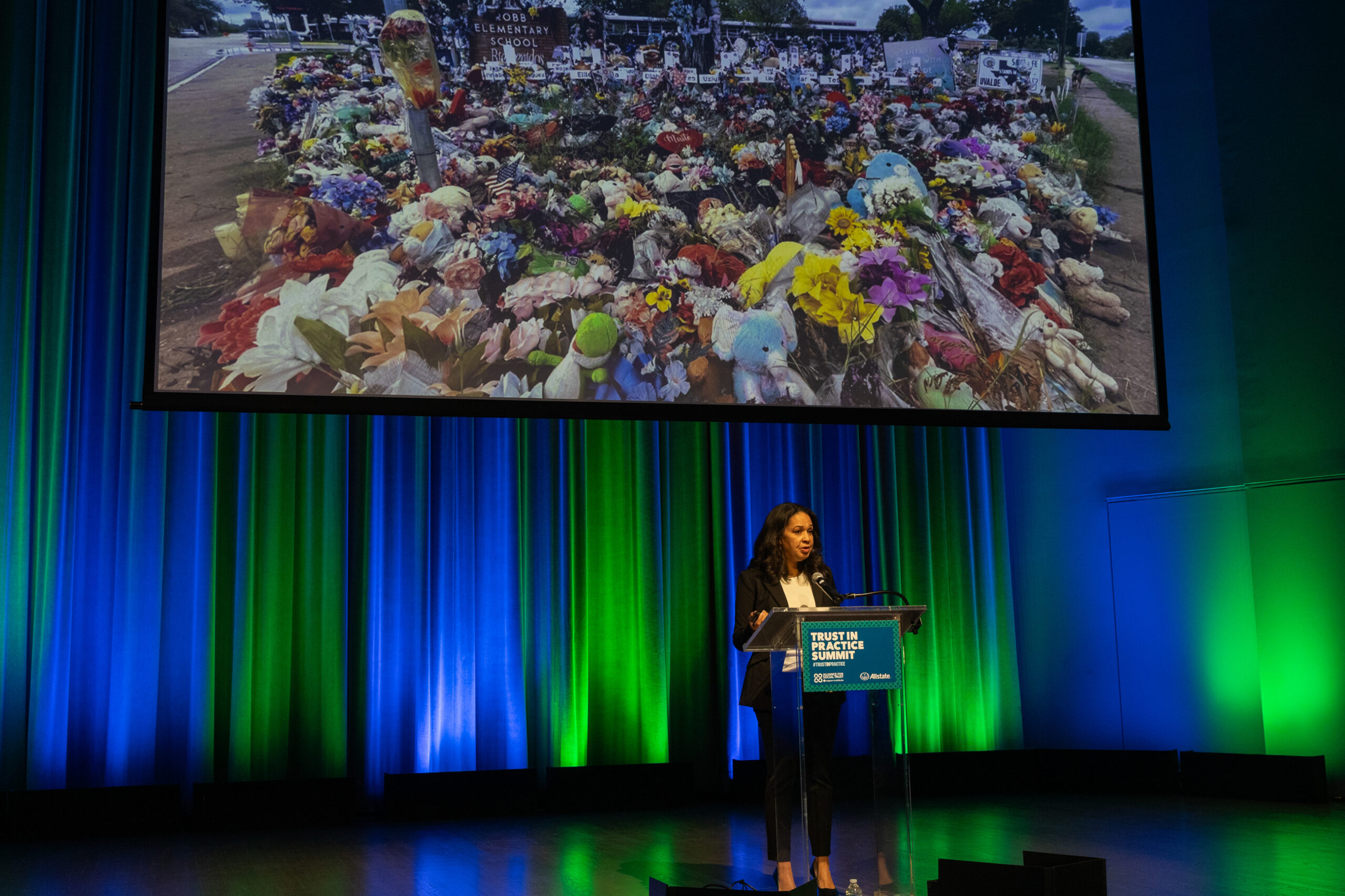 One person standing at a podium presenting with a projector behind them.